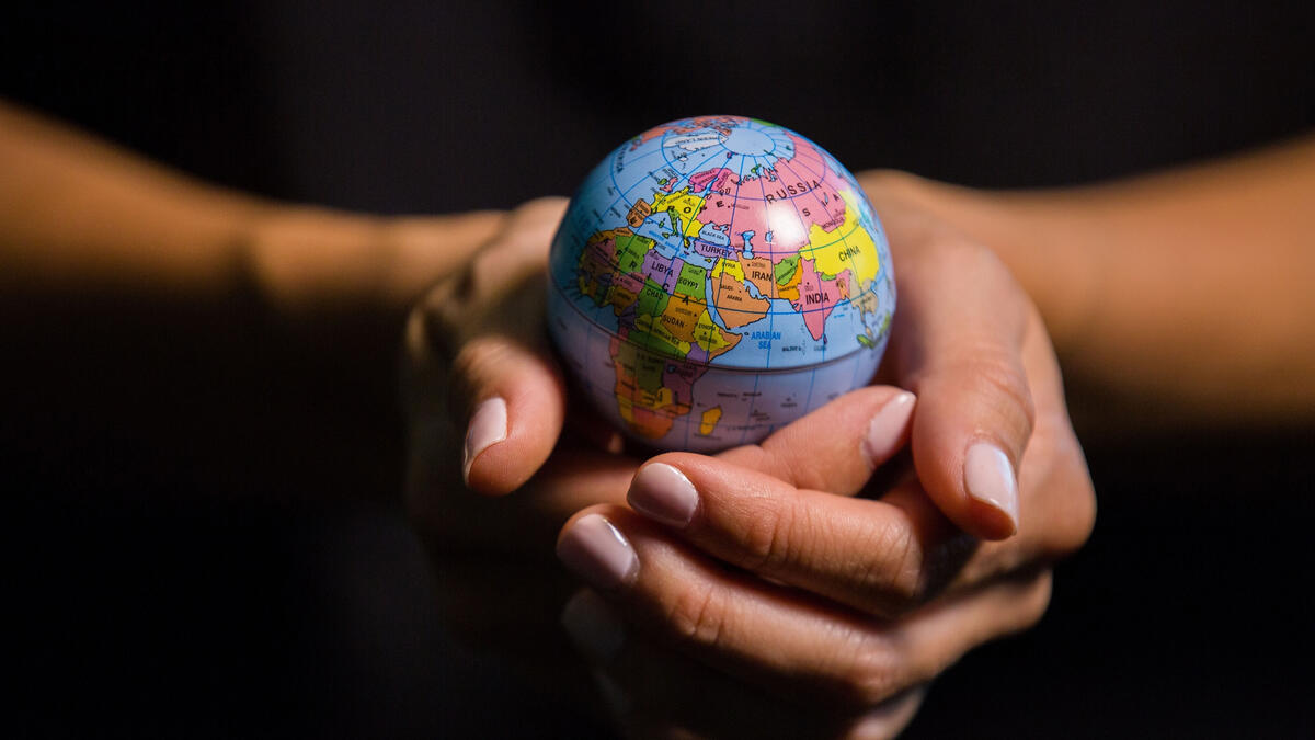 Two hands hold a tiny globe of the Earth