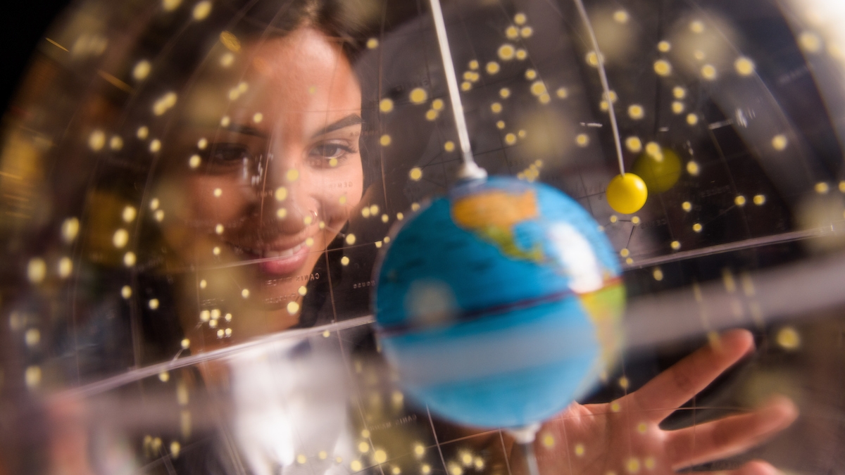 Woman looking at a globe and smiling.