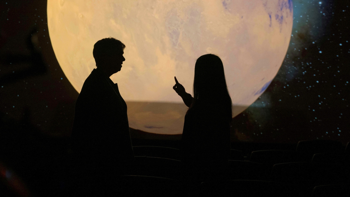 A woman and a young woman are silhouetted against an image of the moon