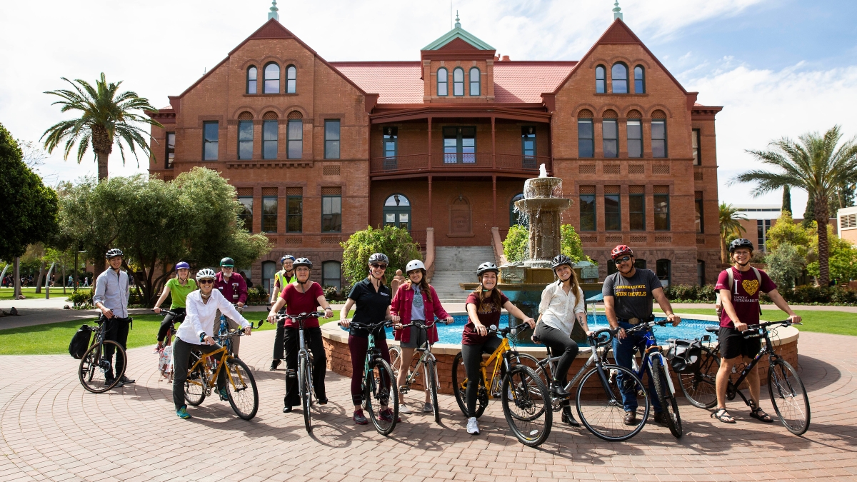 Bicyclists pose for a group photo in front of Old Main