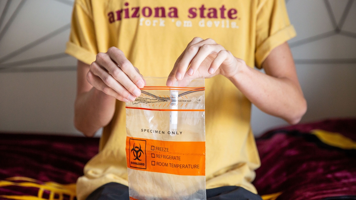 A student puts a test tube into a biohazard bag