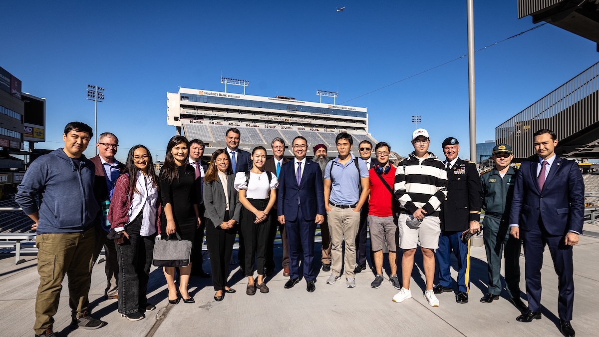 Group photo of ASU Kazakh students posing with Yerzhan Ashikbayev, the Ambassador of the Republic of Kazakhstan to the U.S., with Sun Devil Stadium in the background.