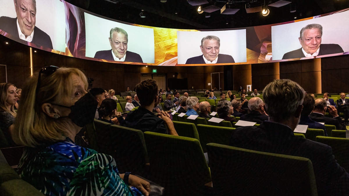 Audience watching Al Gore talk on screens around room
