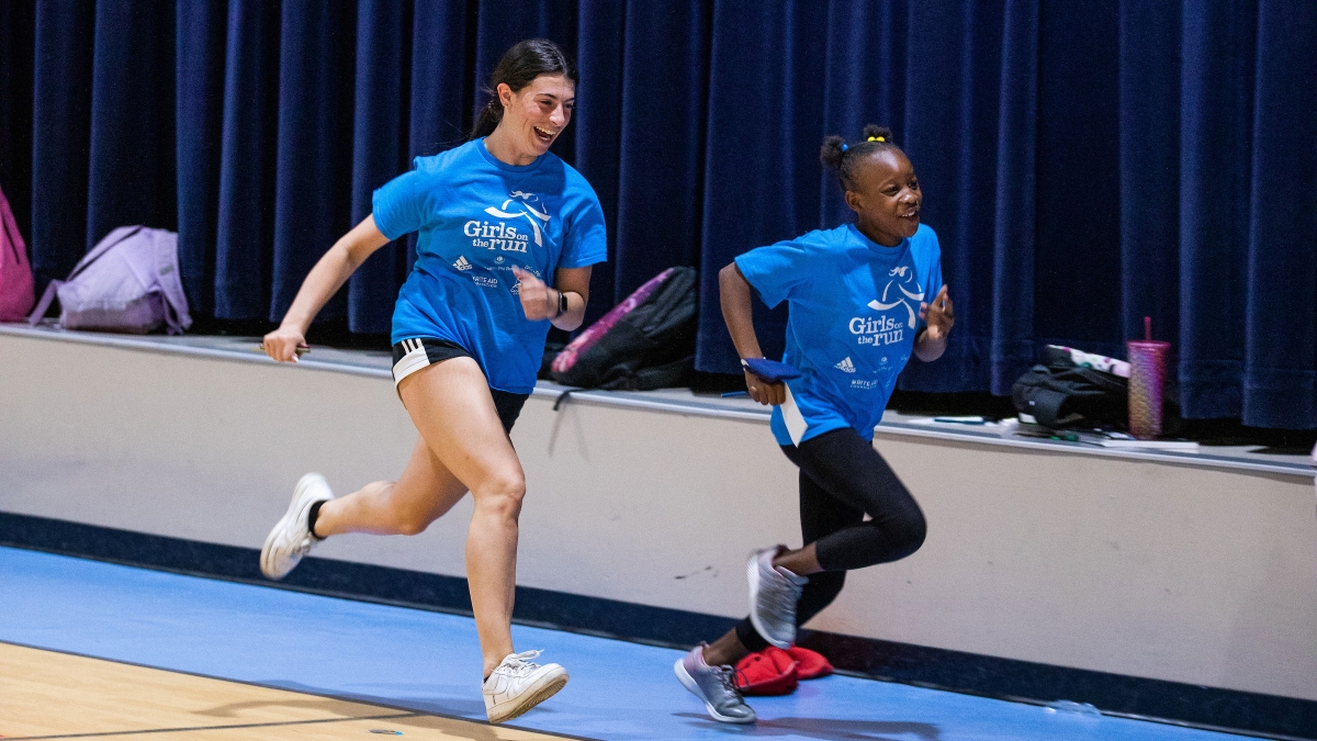 ASU student and elementary school student running in gym