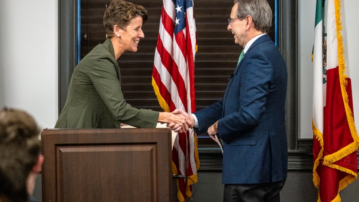 Two people shaking hands behind a lectern.