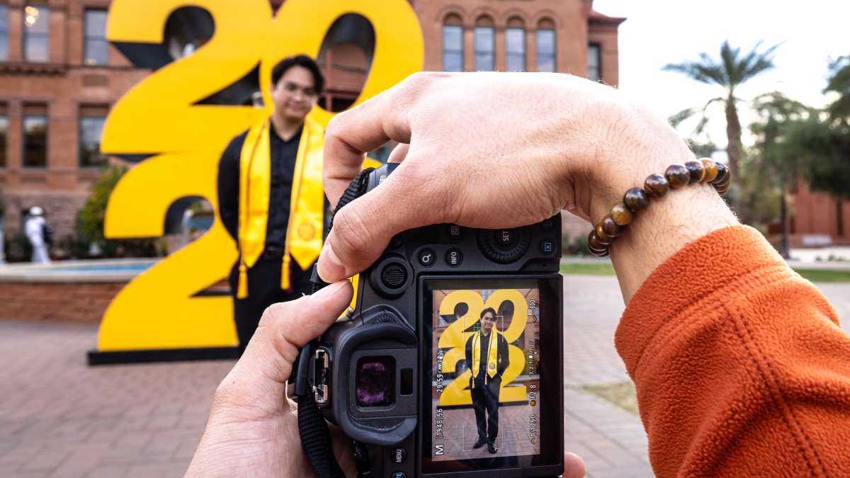 Student having photo taken in front of 2022 sign in front of ASU's Old Main building.
