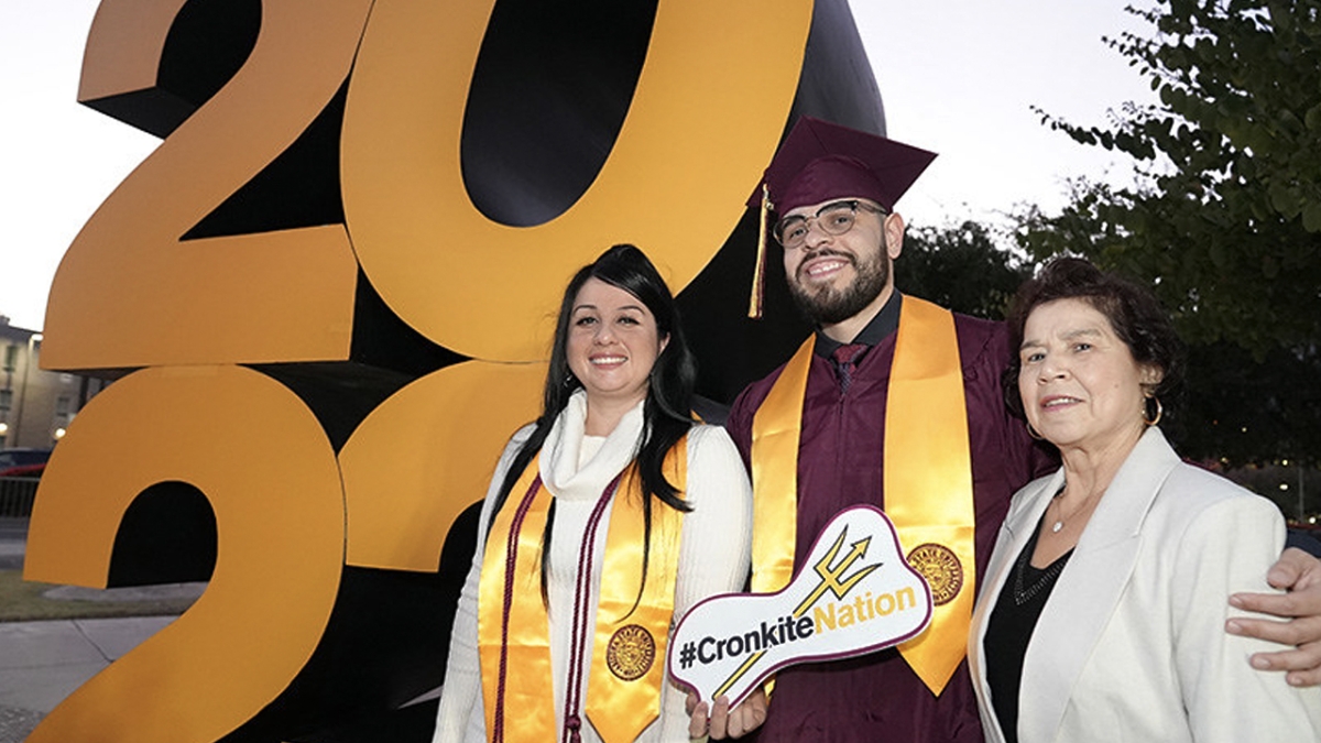 People wearing caps and gowns pose next to a '2023' sign.