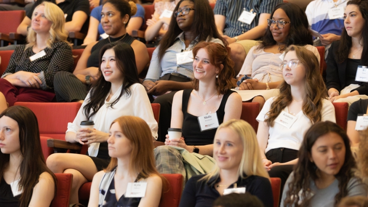 A group of students smiles in an auditorium. 