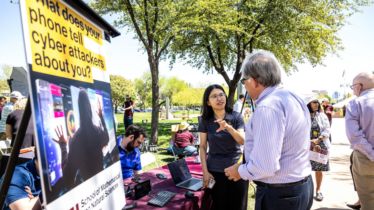 Two people talking at table at outdoor event at Arizona Capitol