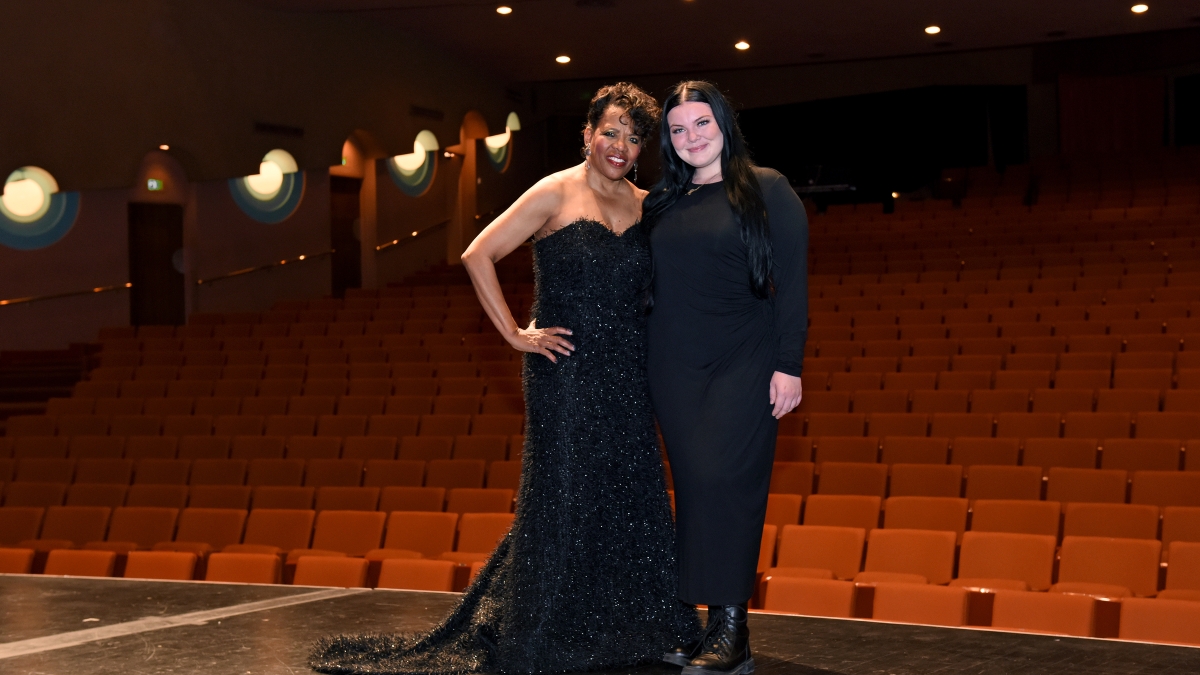Women dressed in black pose in front of an empty theater.