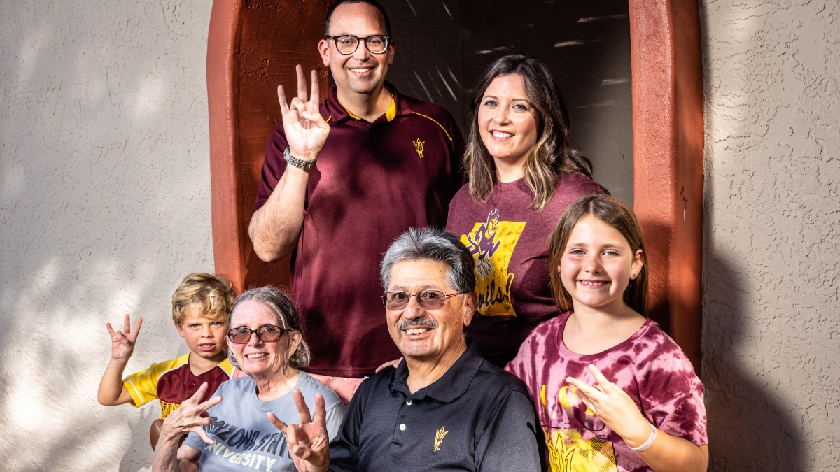 Three generations of a family pose while holding up ASU pitchfork gestures