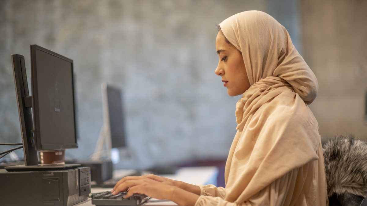A woman wearing a hijab works on a computer