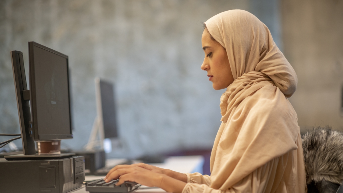 A woman wearing a hijab works on a computer