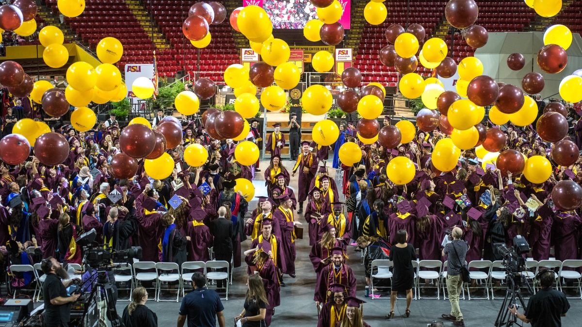 People at a convocation ceremony with balloons falling from the ceiling.