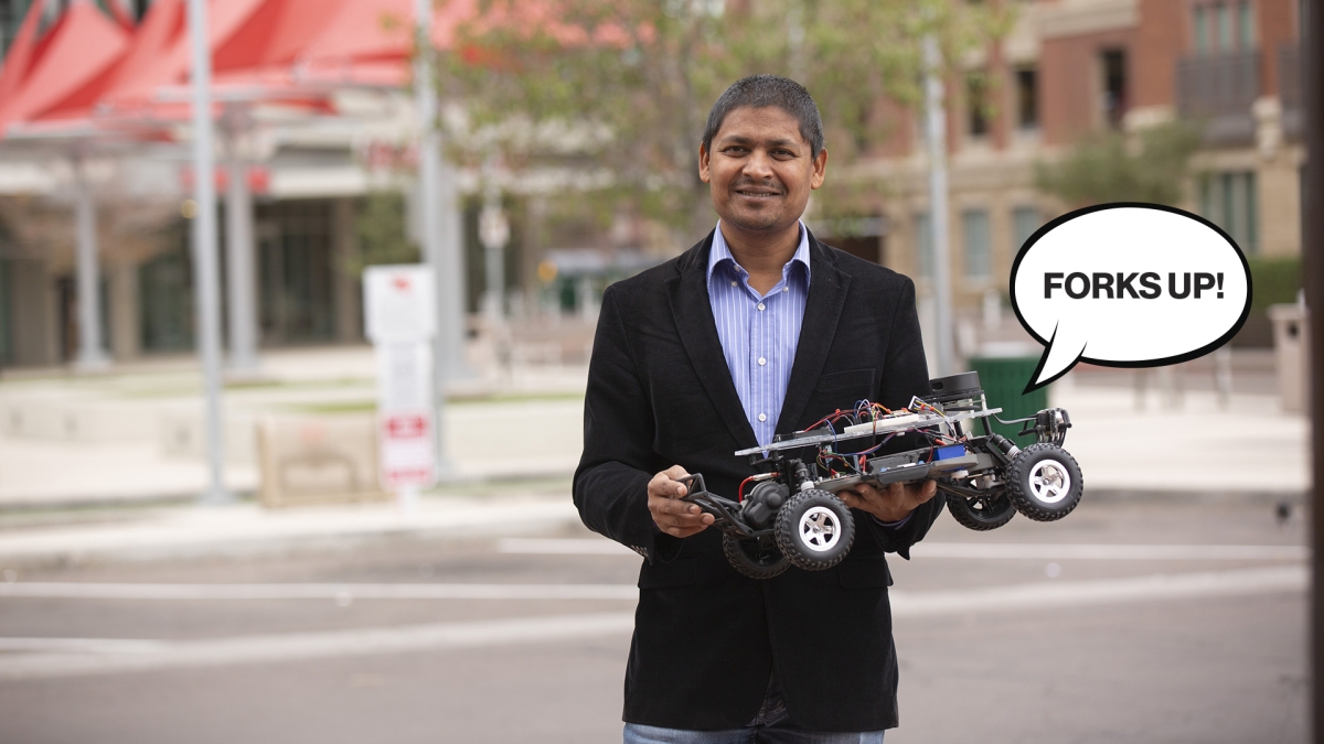 Aviral Shrivastava holding a model car with an illustrated speech balloon that says &quot;Forks Up!&quot;