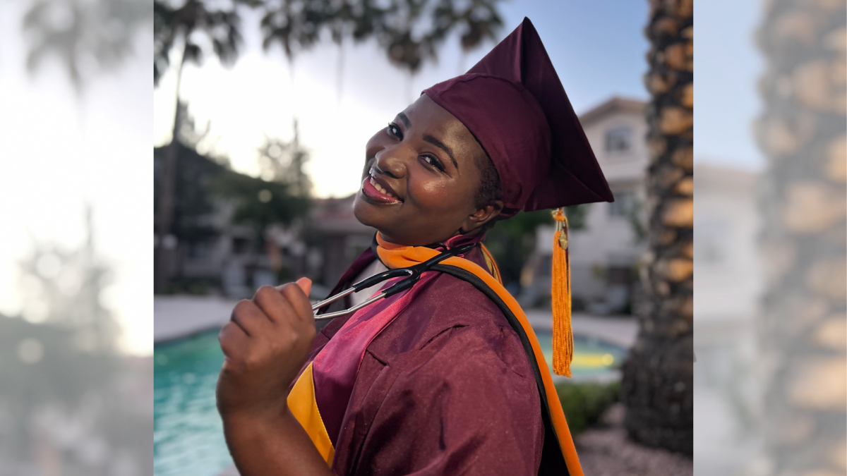 Bilha Obaigwa smiles at the camera wearing her graduation cap and gown and holding a stethoscope in hand. 