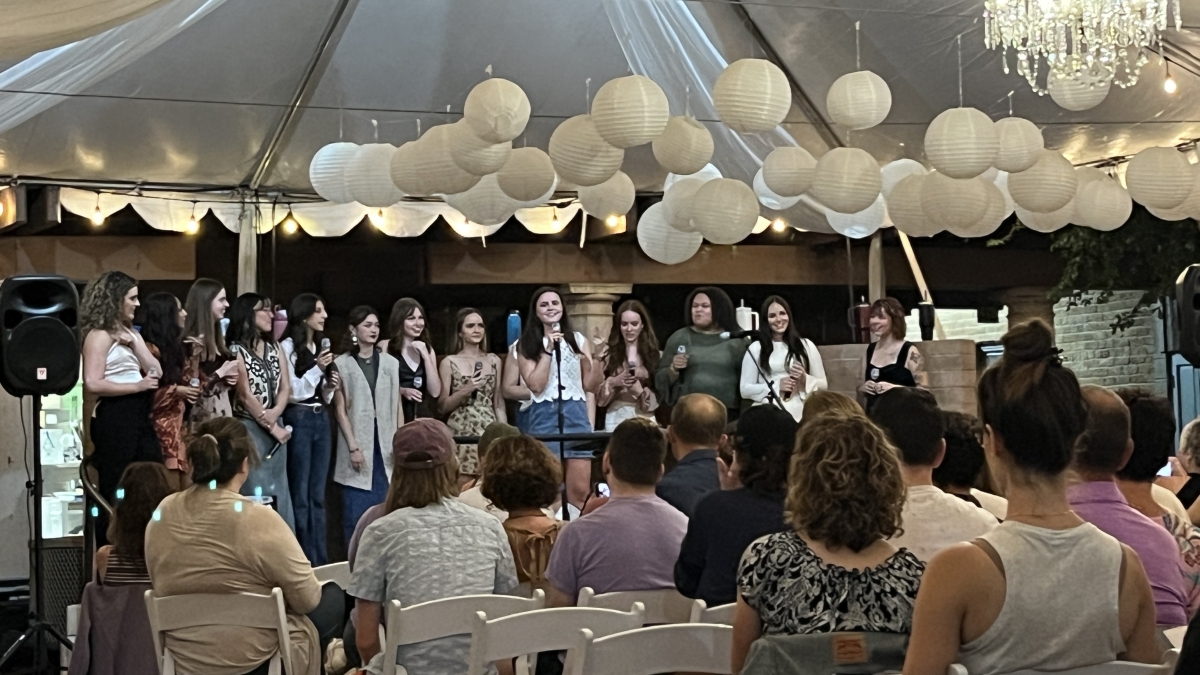 An a cappella group performs on a stage in a tent