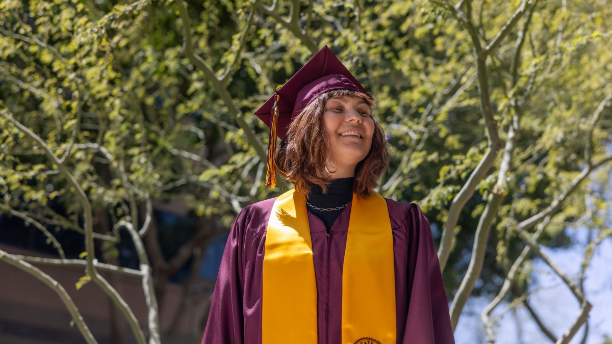 Portrait of Mollie McCurdy in an outdoor setting wearing ASU graduation robe, cap and stole