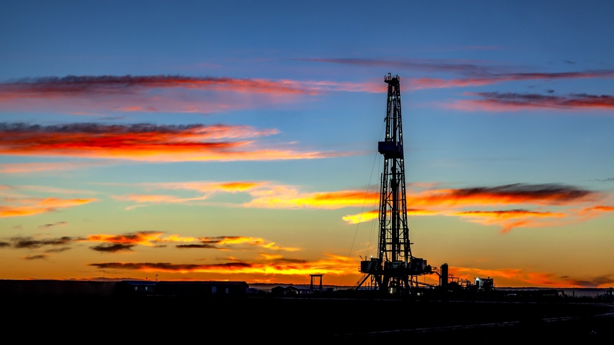 Oil rig shown against a colorful sunset