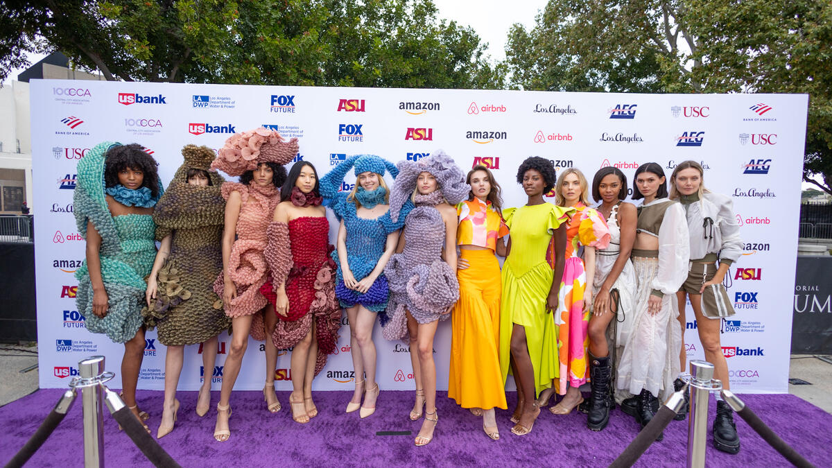 People dressed in an array of colorful fashion designs standing in a line.