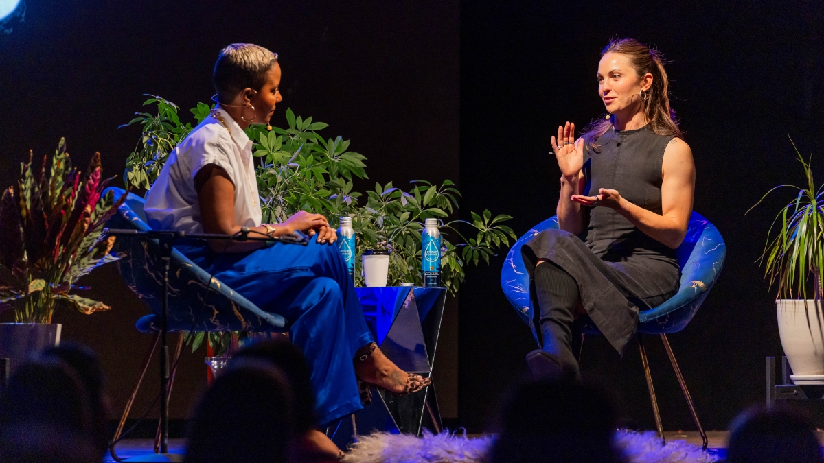 Two women seated on a stage having a discussion.