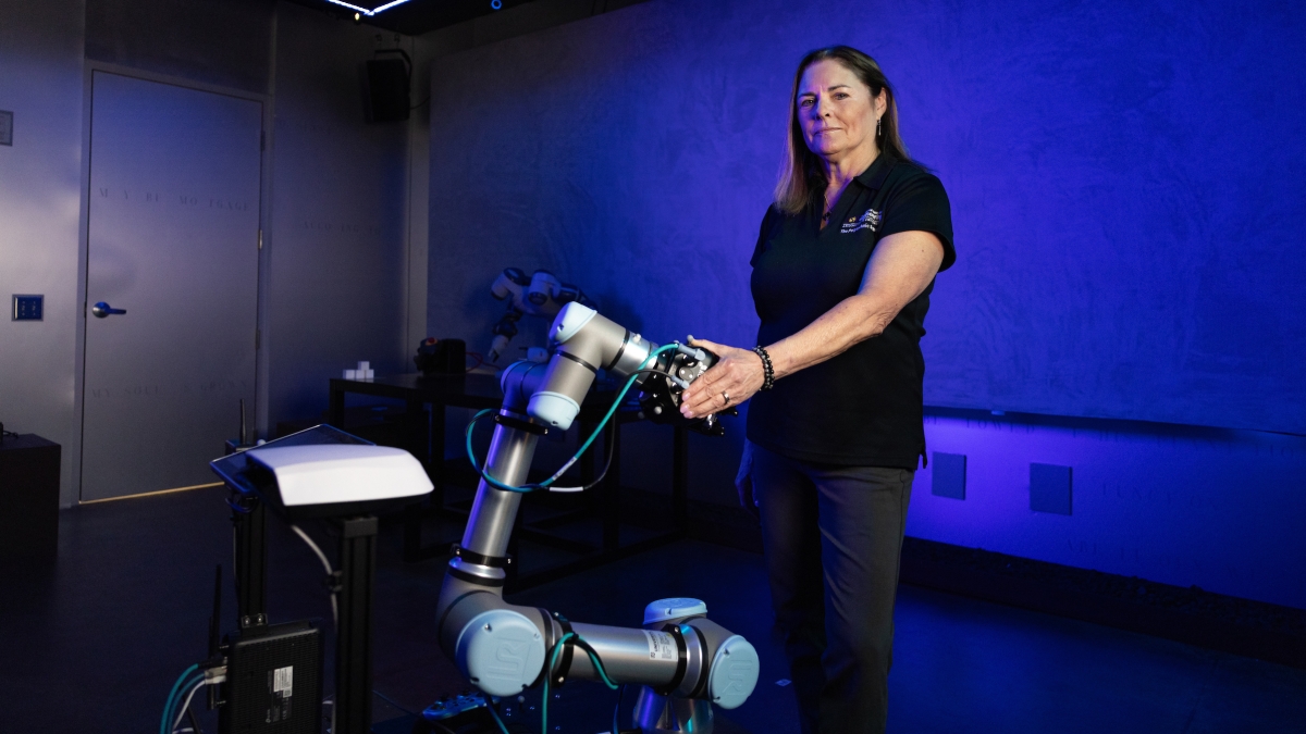 A woman stands next to a robot in a blue-hued room