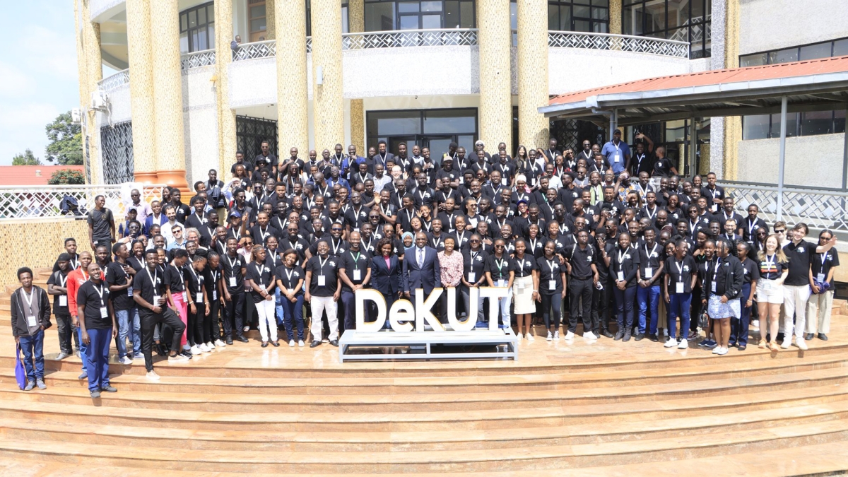 Large group of people pose for a photo at the top of steps leading up to an outdoor building at the Dedan Kimathi University of Technology campus.