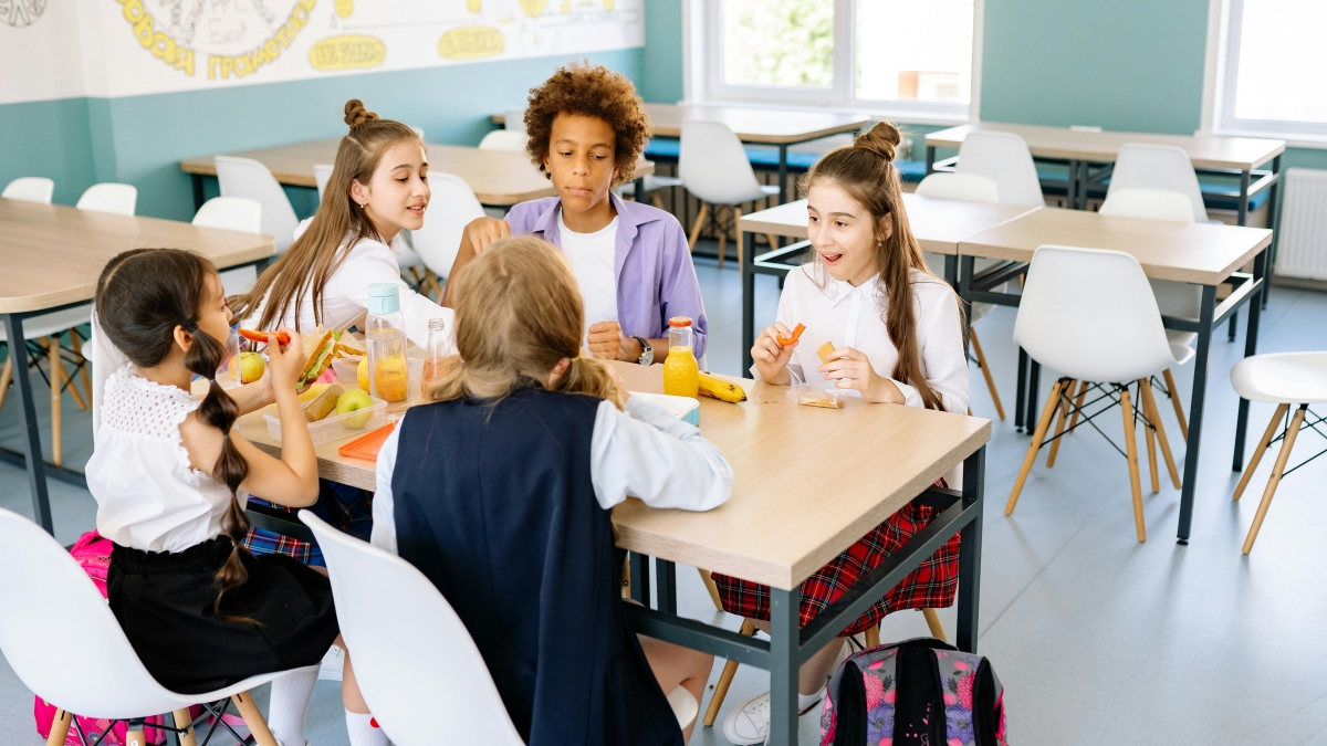 Group of young students eating together at a table.