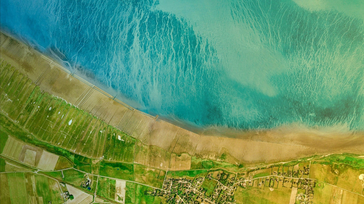 Aerial view of a green coastline and a blue sea.