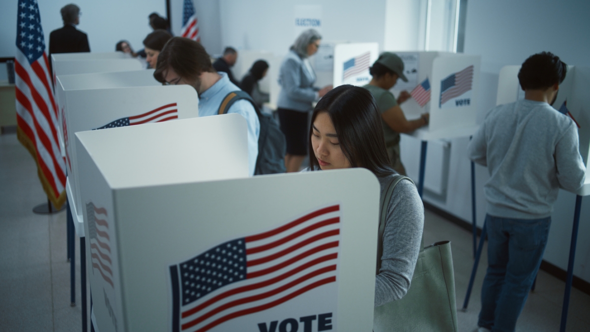 People voting in separate private booths with pictures of the American flag on them.