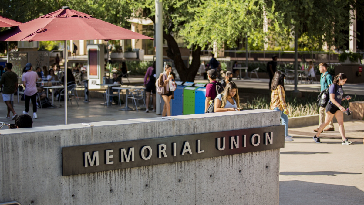 People walk in the background with a sign in the foreground that reads Memorial Union