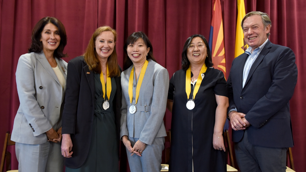 Four women and a man stand in a line for a photo