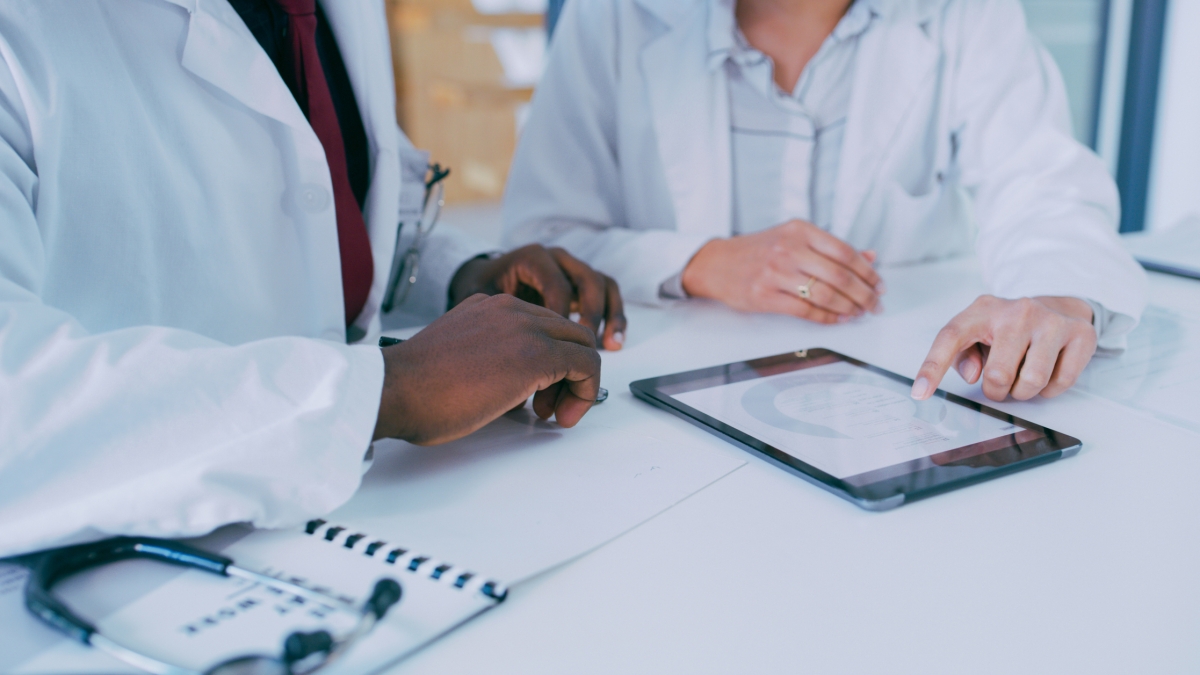 Two doctors in white coats looking at tablet