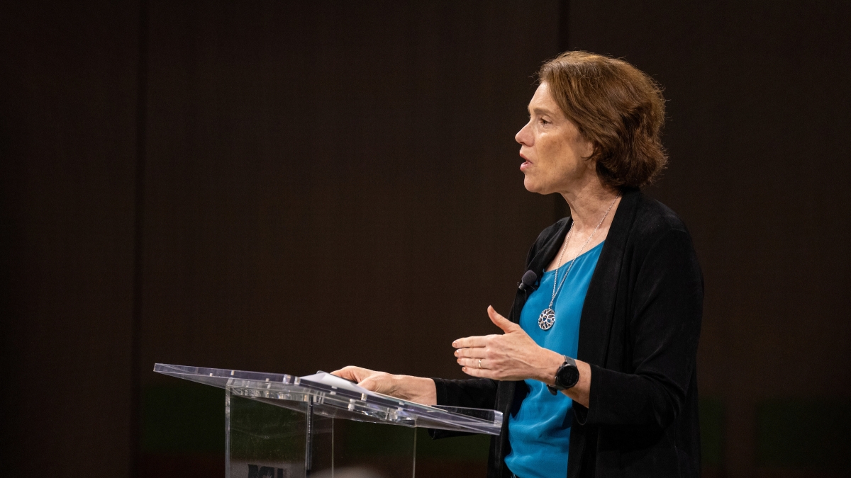 A woman stands at a podium while speaking