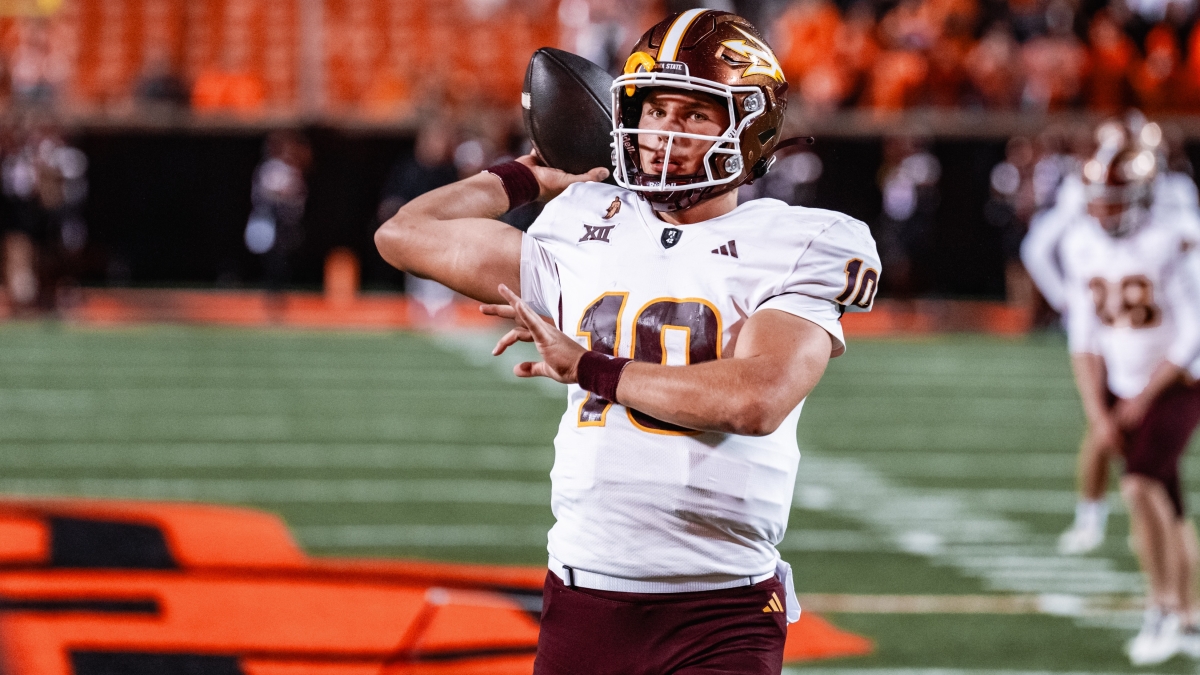 Person in a football uniform and helmet about to throw a football on a field.