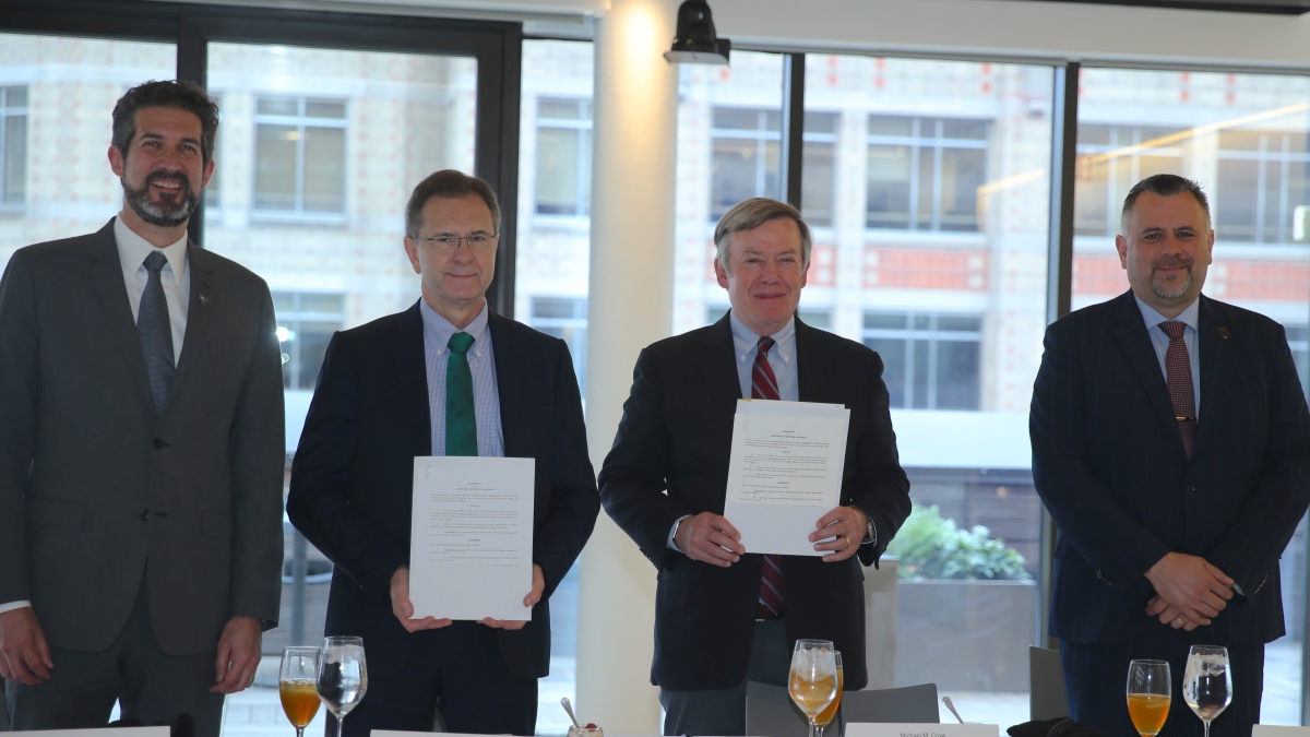 Four men stand behind a table smiling.