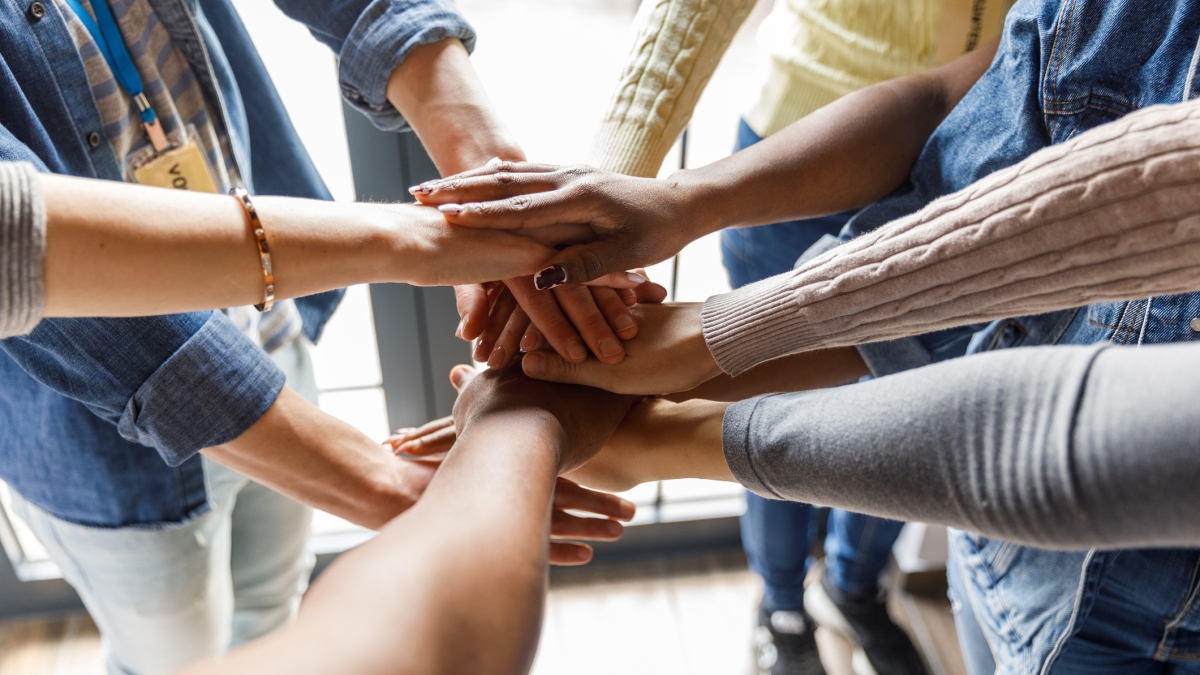 Group of people putting their hands together in the middle of a circle