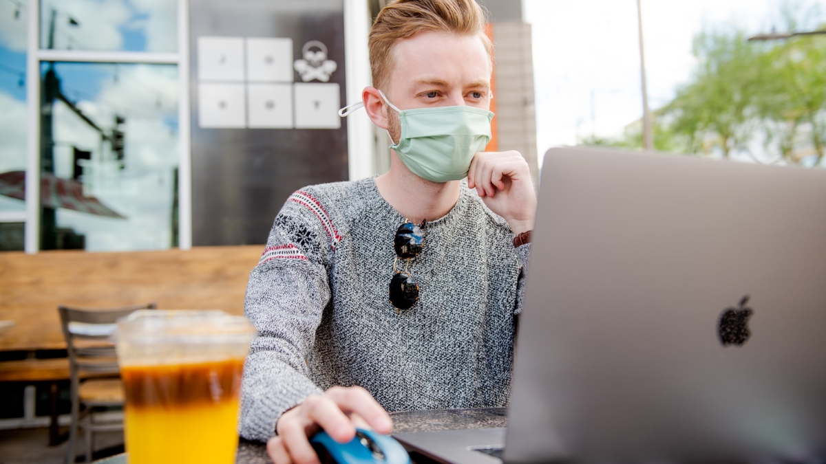 man wearing a mask works at a laptop