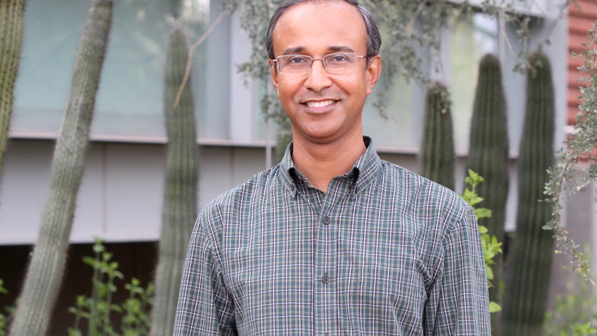 ASU researcher Rahman Masmudur smiling in front of some cacti, wearing glasses and a button down shirt
