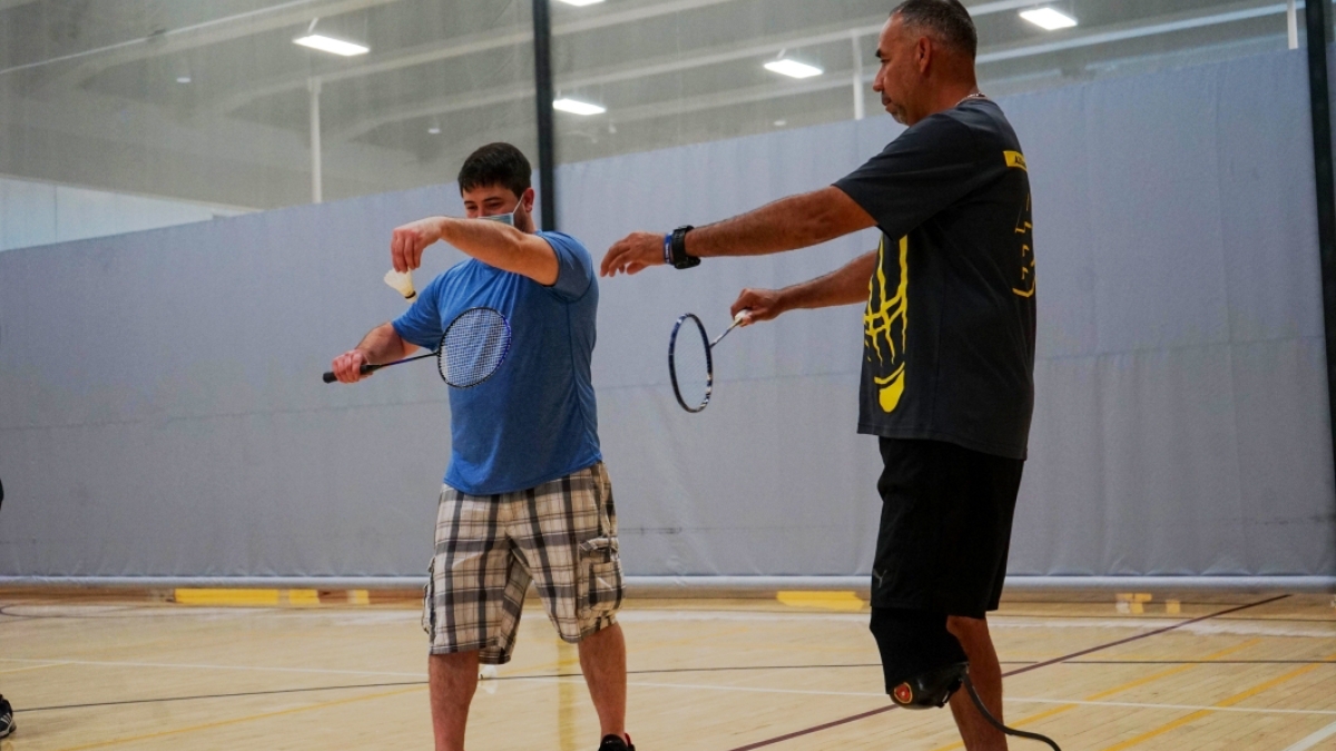 person being taught out to serve a badminton shuttlecock