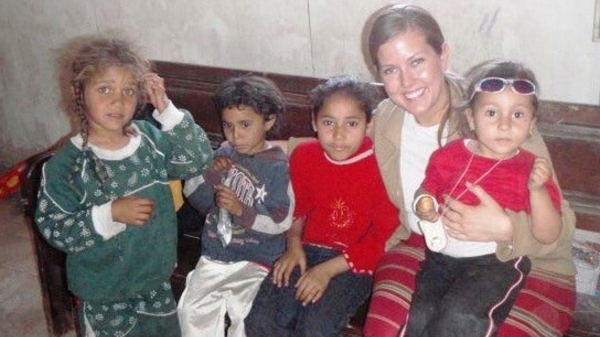 Danielle Wofford sits with three children on a couch in rural Egypt during as part of a community outreach visit