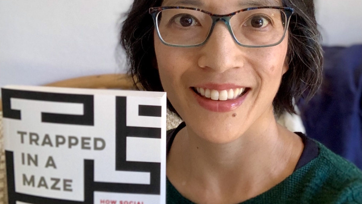 ASU sociology Professor Leslie Paik holding up a copy of her book "Trapped in a Maze: How Social Control Institutions Drive Family Poverty and Inequality"