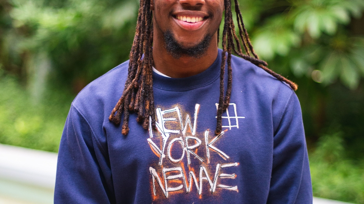 Portrait of ASU student Atllas Hopkins, wearing a blue sweatshirt and smiling in an outdoor setting.