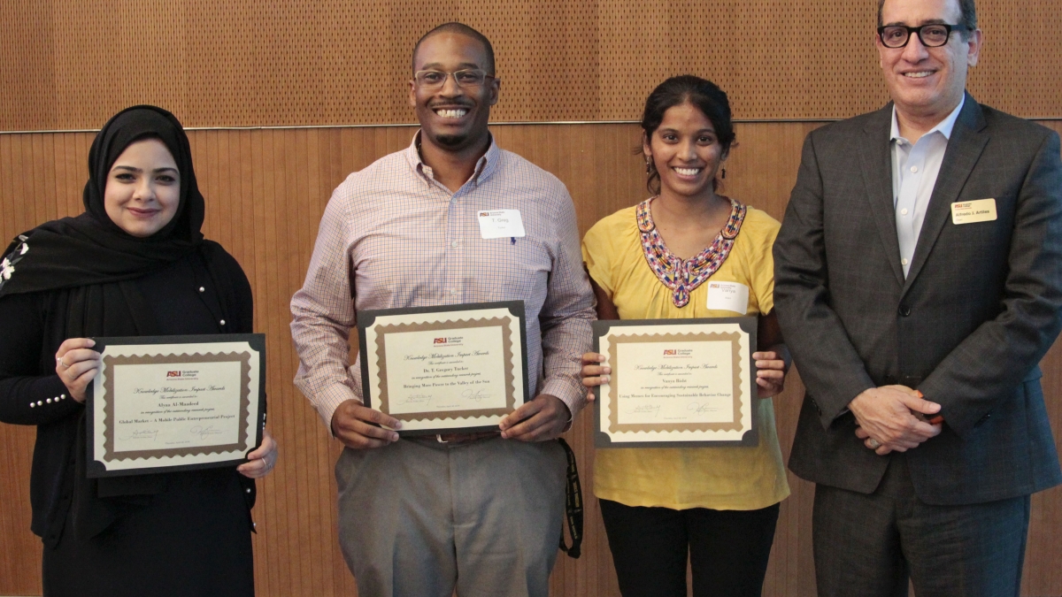 The three broadly smiling awardees show off their certificates alongside the Dean.