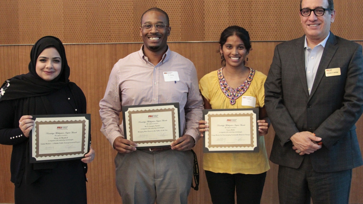 The three broadly smiling awardees show off their certificates alongside the Dean.