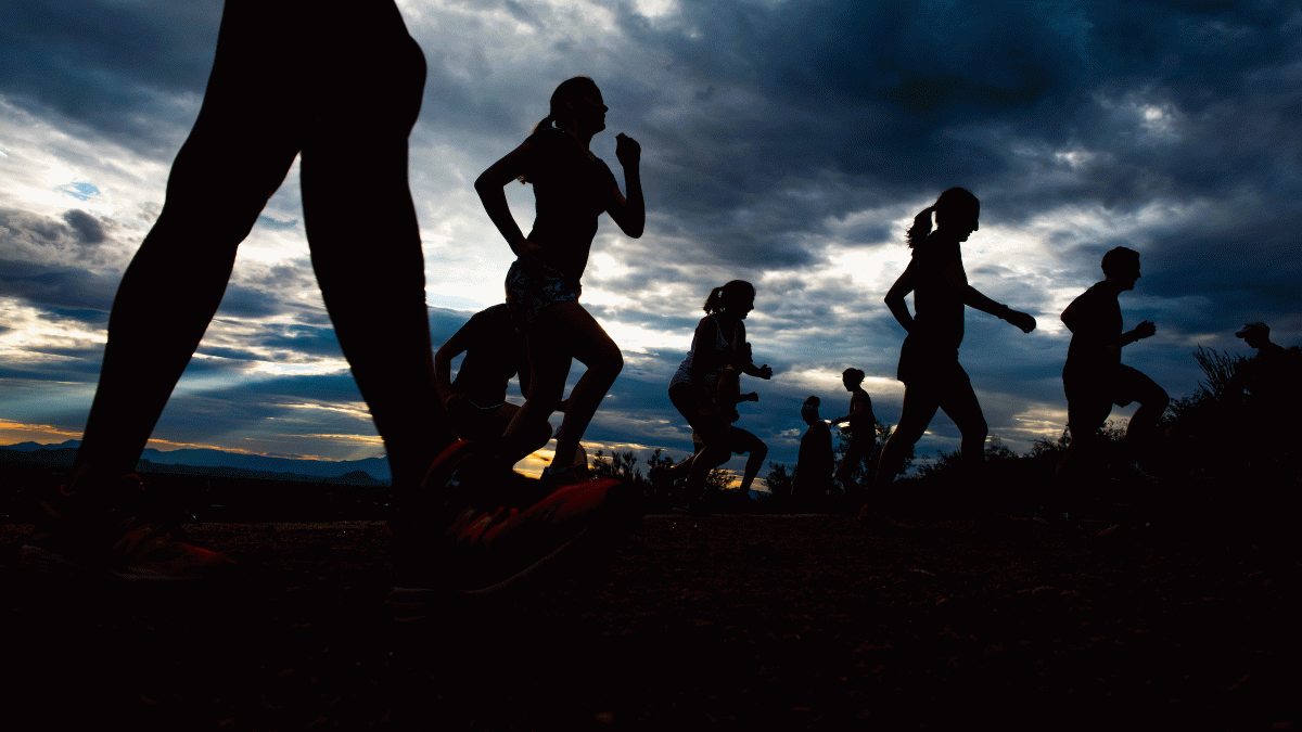 People running are silhouetted against the sunrise