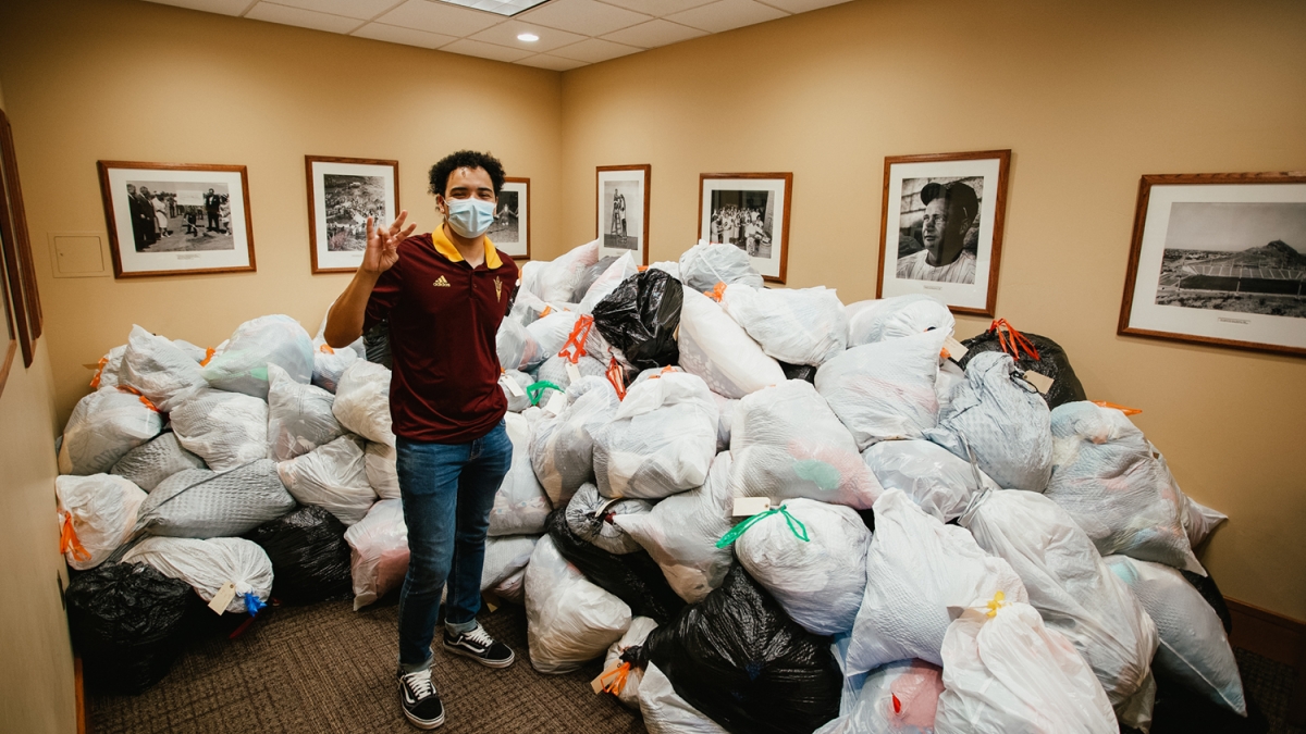 ASU student Ahlias Jones stands by nearly 2,000 pounds of clothing donated by students in the Medallion Scholarship Program