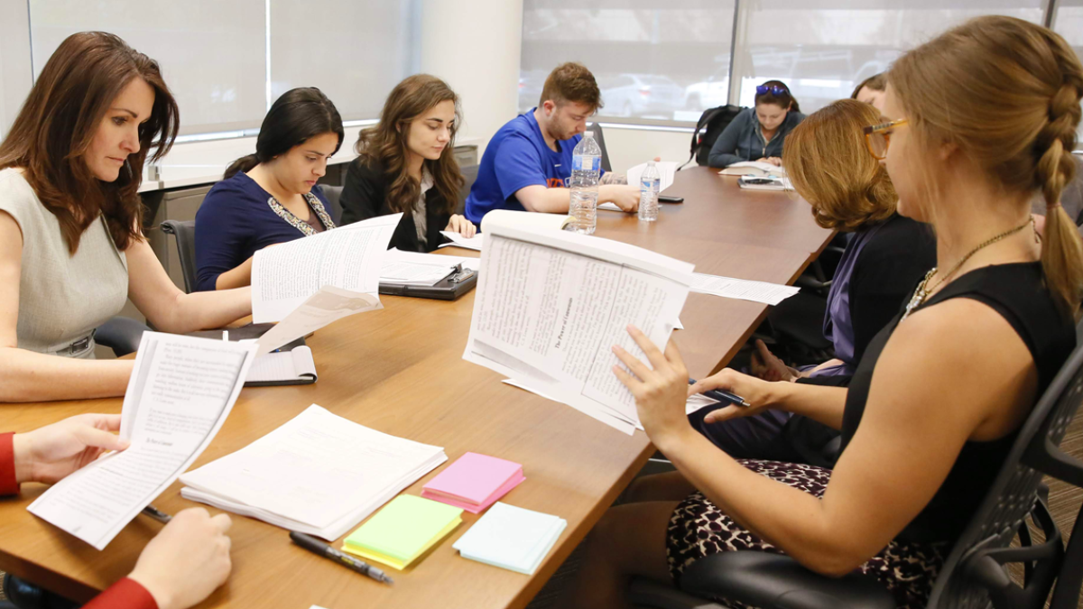 law students sitting at a conference table reading documents