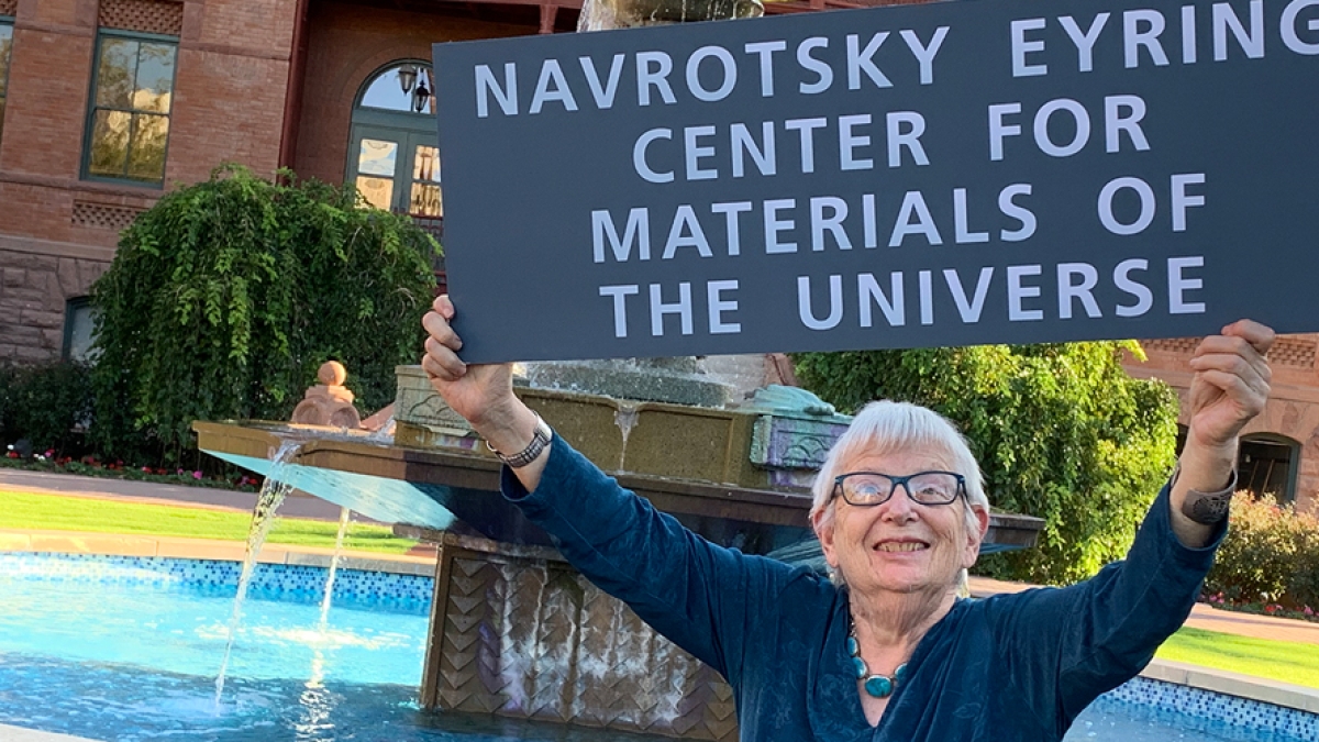 Professor Alexandra Navrotsky holds a sign for the opening of the Navrotsky Eyring Center for Materials of the Universe