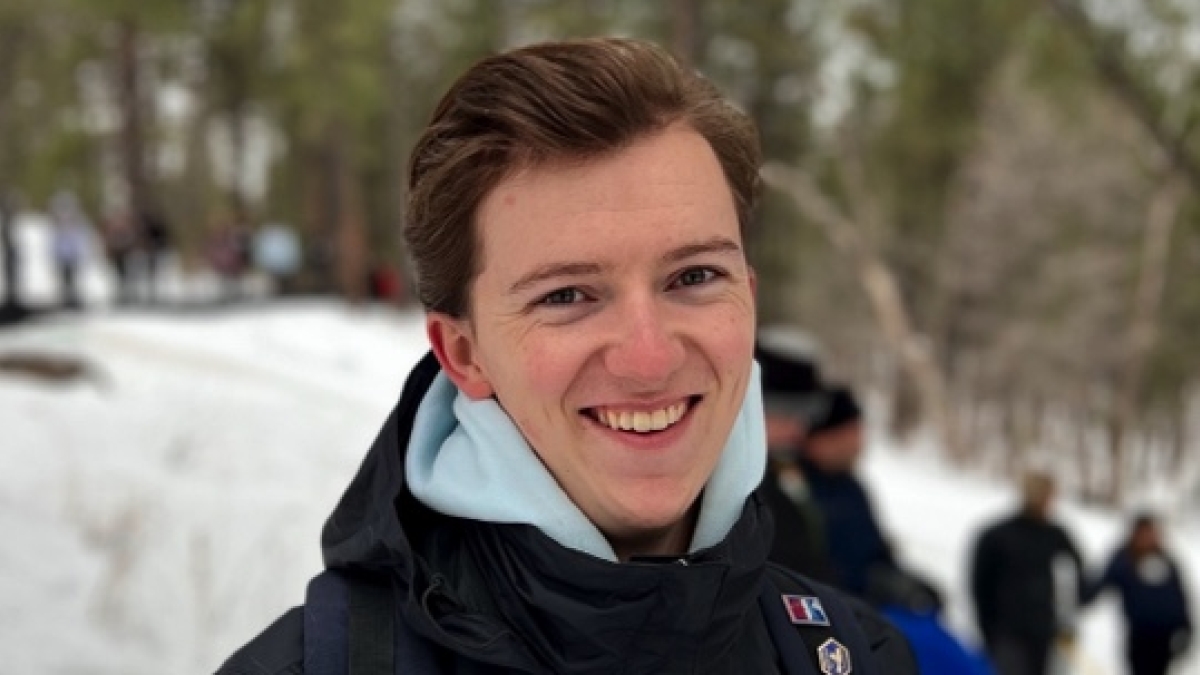 A person in a jacket smiles in the middle of a snowy field